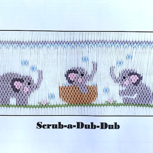 May include: Cross-stitch pattern featuring three gray elephants with pink ears and trunks. One elephant is in a woven basket. The text "Scrub-a-Dub-Dub" is below the elephants. The pattern includes blue bubbles and pink flowers.