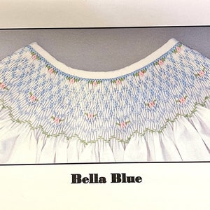 May include: White garment with a detailed blue smocked yoke, accented with small pink floral embroidery and green trim. The text "Bella Blue" is displayed at the bottom of the image. The design is reminiscent of children's clothing.