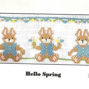 May include: A cross-stitch pattern featuring three brown bunnies wearing blue shirts and holding flowers. The pattern is titled "Hello Spring" and is from Crossed Eyed Cricket.