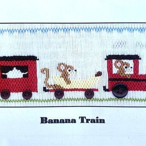 May include: A cross-stitch pattern for a children's nursery featuring a red train with a banana car and three teddy bears. The pattern is titled "Banana Train" and is from Crossed Cricket, 2023, Plate #554.