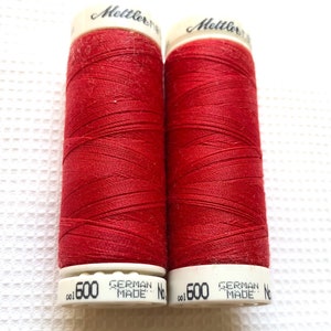 May include: Two spools of red thread, each labeled "Mettler", "German Made", and "col 600".