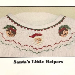 May include: A white fabric with a red, green, and white embroidered design of Santa Claus and two elves. The text "Santa's Little Helpers" is printed below the design.