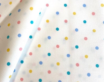 May include: White fabric with a repeating pattern of small blue, yellow, and pink polka dots.