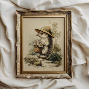 May include: Framed watercolor print of a hedgehog wearing a straw hat and carrying a basket of daisies. The artwork has a vintage aesthetic with a neutral color palette, set in a decorative, ornate gold frame. The image is on a white background.