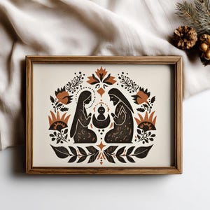 May include: A framed print depicting a Nativity scene in a stylized design. The image shows two figures either side of a baby, with floral and leaf patterns in black, brown, and cream. The wooden frame provides a rustic aesthetic.