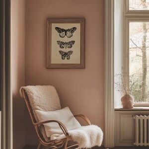 Puede incluir: Una mecedora con una manta de piel de oveja blanca y una almohada se encuentra en una esquina de una habitaci&oacute;n con una impresi&oacute;n enmarcada de tres mariposas en una pared rosa.