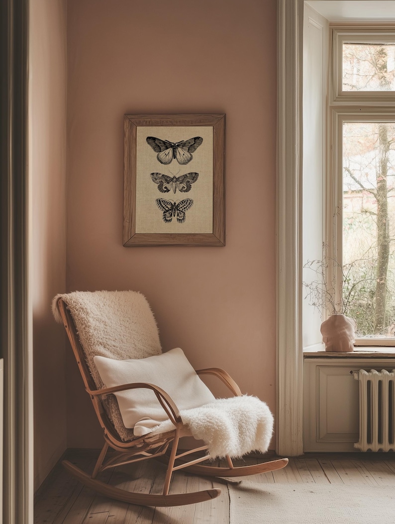 Puede incluir: Una mecedora con una manta de piel de oveja blanca y una almohada se encuentra en una esquina de una habitaci&oacute;n con una impresi&oacute;n enmarcada de tres mariposas en una pared rosa.