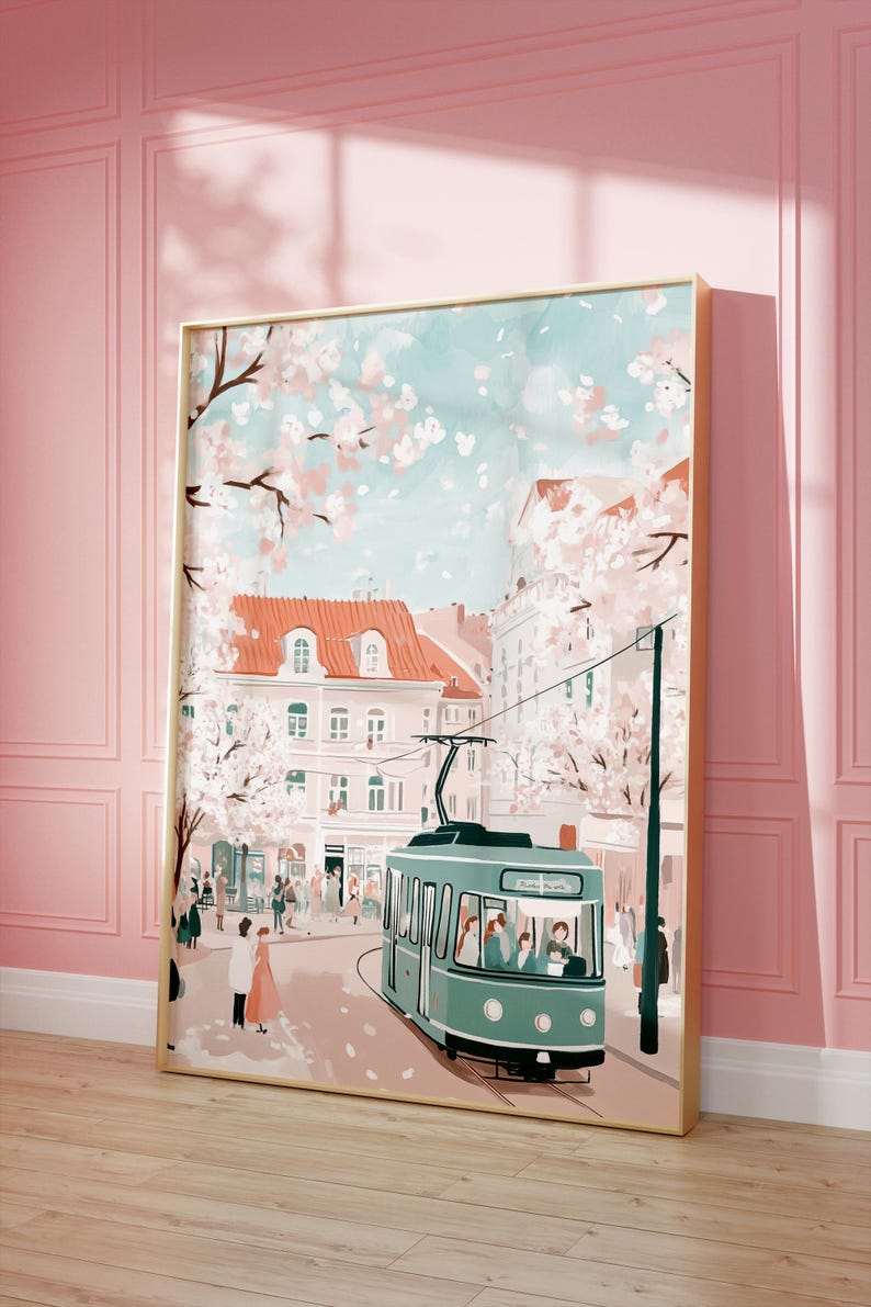 May include: A vintage-style illustration of a city street scene with a green tram, pink buildings, and cherry blossom trees. The tram is filled with passengers and is traveling down a street lined with trees. The sky is a light blue with white clouds.