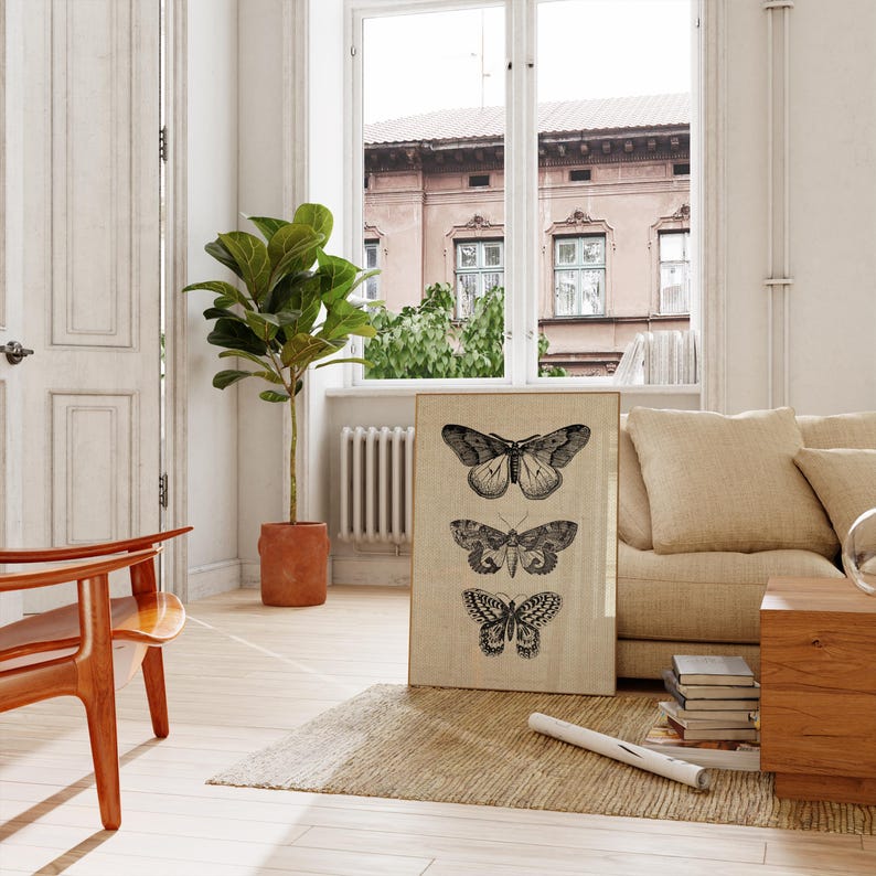 Puede incluir: Una impresi&oacute;n enmarcada con un fondo beige que presenta tres ilustraciones en blanco y negro de mariposas. Las mariposas est&aacute;n dispuestas verticalmente en una fila, con la mariposa m&aacute;s grande en la parte superior y la m&aacute;s peque&ntilde;a en la parte inferior. La impresi&oacute;n est&aacute; colgada en una pared blanca en un sal&oacute;n.
