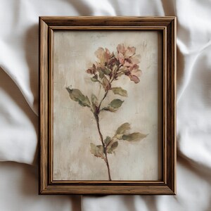 May include: A framed floral painting featuring a sprig of pink and yellow flowers with green leaves. The artwork is set against a neutral background and framed in a gold-toned wooden frame, creating a vintage aesthetic.