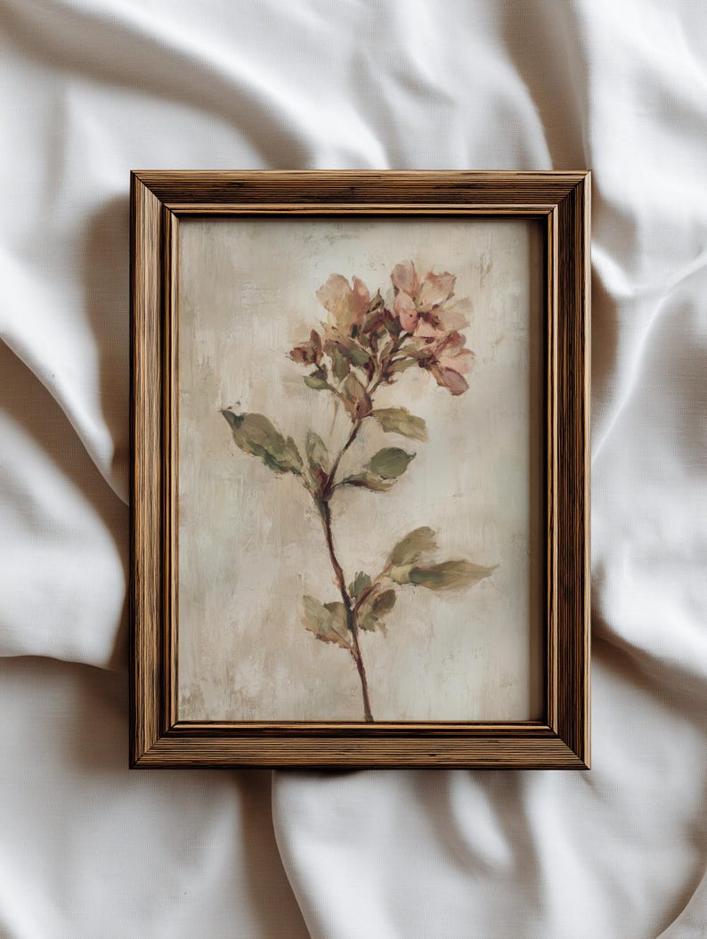 May include: A framed floral painting featuring a sprig of pink and yellow flowers with green leaves. The artwork is set against a neutral background and framed in a gold-toned wooden frame, creating a vintage aesthetic.