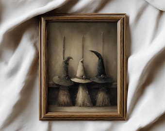 May include: A framed print featuring three witch hats atop brooms. The hats are in shades of gray and beige, with a rustic, vintage aesthetic. The brooms have straw bristles. The artwork is set against a neutral background.