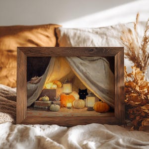 May include: A framed print showing a Halloween scene with a black cat, pumpkins, and lanterns under a draped canopy. The wooden frame surrounds the artwork, which has a warm colour palette of orange, yellow, and brown.