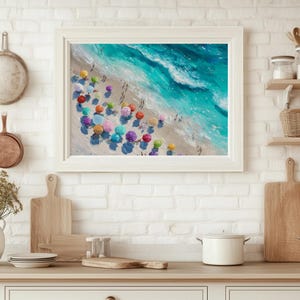 May include: A framed painting shows a beach scene with turquoise waves and colourful beach umbrellas. The artwork is in a white frame, adding a coastal touch to the kitchen. The painting is a vibrant depiction of a sunny day at the beach.