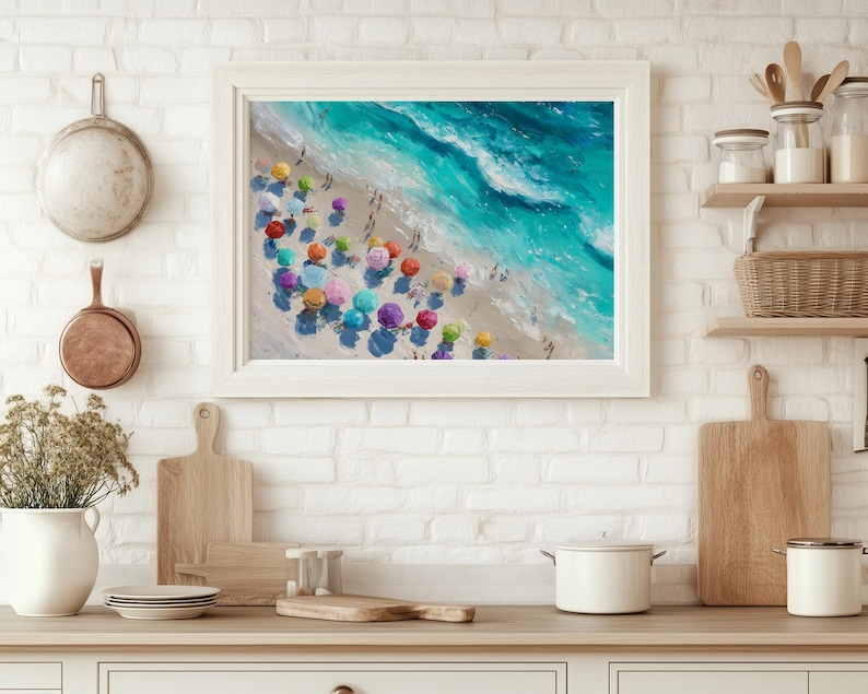 May include: A framed painting shows a beach scene with turquoise waves and colourful beach umbrellas. The artwork is in a white frame, adding a coastal touch to the kitchen. The painting is a vibrant depiction of a sunny day at the beach.