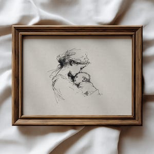 Puede incluir: Un boceto en blanco y negro enmarcado de una madre y un niño. La obra de arte está en un marco de madera marrón. El boceto representa a una madre acunando a un bebé, con líneas y sombreados delicados.