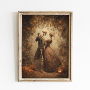 Op de afbeelding: Een ingelijst kunstwerk in vintage-stijl met een dansend skeletpaar. Het kunstwerk heeft een warm kleurenpalet met pompoenen en bladeren, wat een Halloween- of herfstthema cre&euml;ert. De lijst is licht en neutraal.