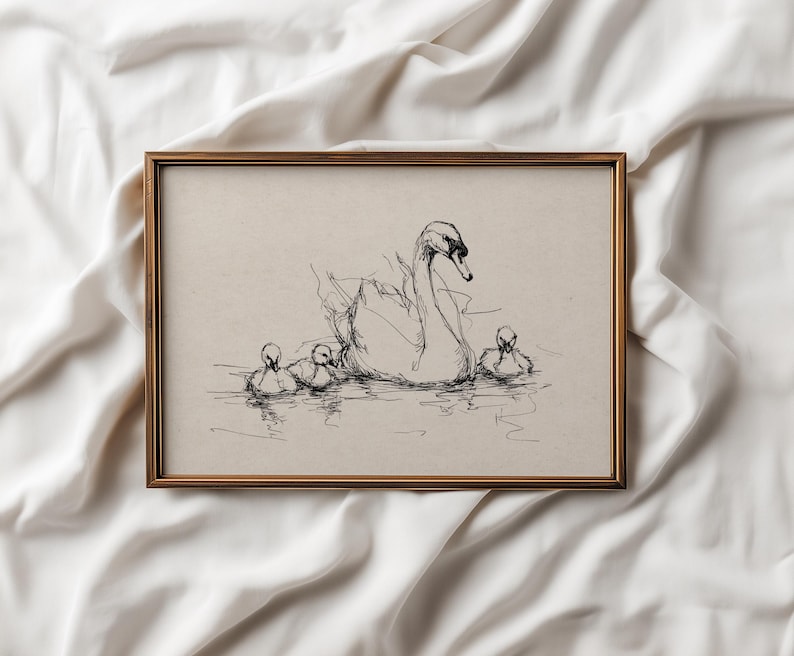 May include: A framed pen and ink drawing of a swan and cygnets. The artwork features a mother swan with three cygnets swimming in the water. The frame is a gold color and the background is a neutral beige.