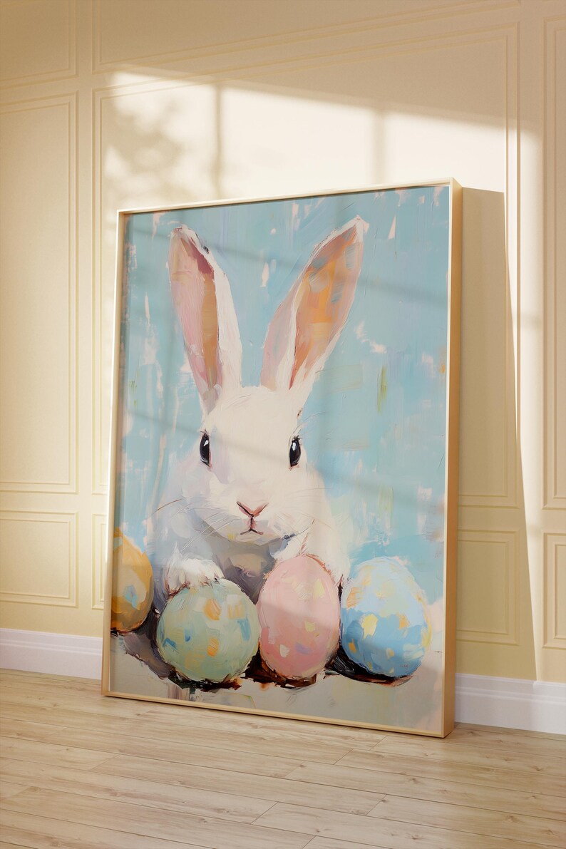 May include: A white rabbit with pink ears sits surrounded by four colorful Easter eggs. The eggs are painted in shades of blue, yellow, pink, and green. The background is a light blue with a white speckled pattern.