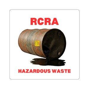 May include: A sticker featuring a rusty metal barrel spilling black liquid. The text "RCRA" is above the barrel, and "HAZARDOUS WASTE" is below it, all in red. The background is white.