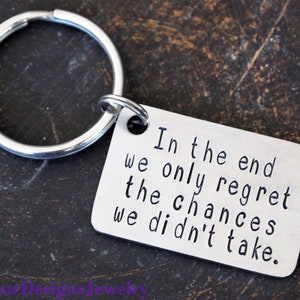 May include: Silver keychain with a rectangular tag that reads "In the end we only regret the chances we didn't take."