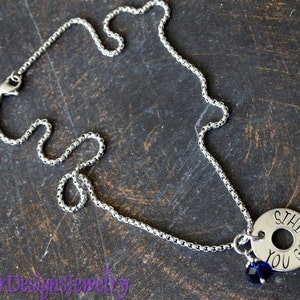 May include: A silver chain necklace with a silver charm that reads "Still You Got" and a small blue crystal charm.