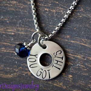 May include: Silver necklace with a round charm that says "You got this" and a dark blue crystal bead.