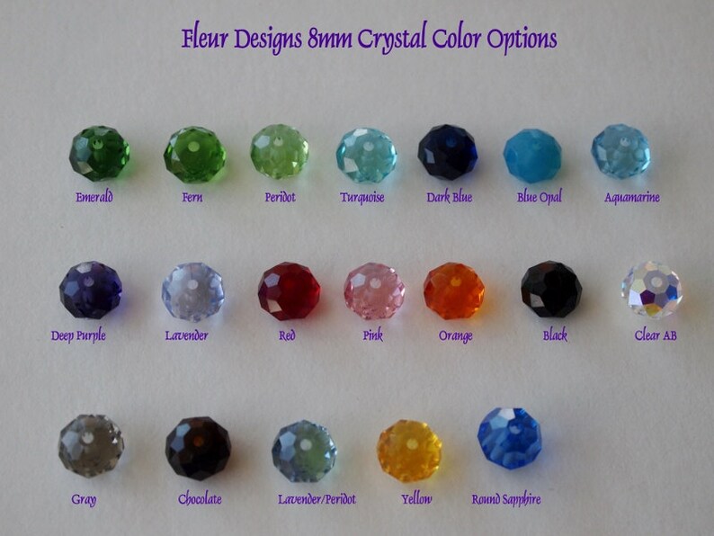 May include: A chart showing 8mm crystal color options for jewelry making. The colors include emerald, fern, peridot, turquoise, dark blue, blue opal, aquamarine, deep purple, lavender, red, pink, orange, black, clear AB, gray, chocolate, lavender/peridot, yellow, and round sapphire.