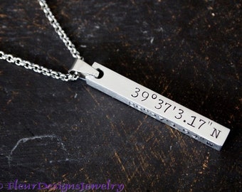 May include: Silver necklace with a bar pendant engraved with the coordinates 39°37'3.17" N.
