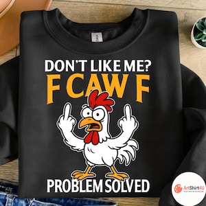 May include: Black sweatshirt with the text "DON'T LIKE ME? FCAW F PROBLEM SOLVED" in white and yellow. A cartoon chicken with a red comb and wattle is giving the middle finger with both hands.