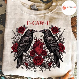 Puede incluir: Sudadera color crema con un dise&ntilde;o g&oacute;tico. Presenta dos cuervos negros enfrentados, rosas rojas y un coraz&oacute;n rojo. El texto "F-CAW-F" est&aacute; impreso encima de los cuervos. El dise&ntilde;o est&aacute; centrado en la parte delantera.