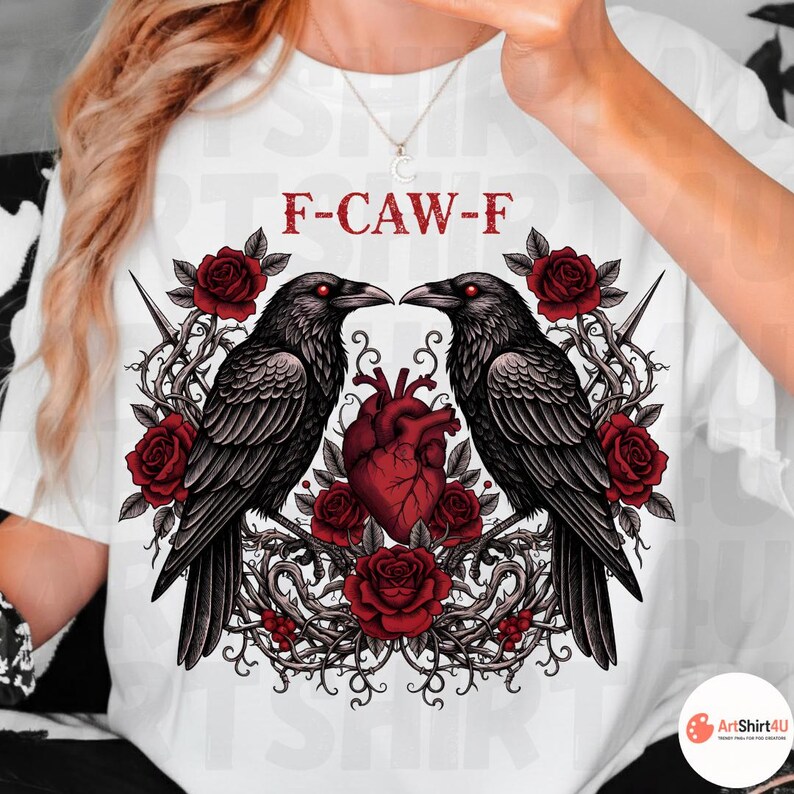 Puede incluir: Camiseta blanca con un dise&ntilde;o g&oacute;tico. Dos cuervos negros se enfrentan, rodeados de rosas rojas y un coraz&oacute;n rojo. El texto "F-CAW-F" est&aacute; impreso encima del dise&ntilde;o. El dise&ntilde;o est&aacute; centrado en la camiseta.
