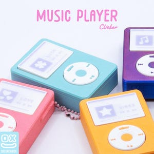 May include: A collection of colorful music player-shaped clickers in shades of pink, blue, purple, and yellow. Each clicker has a screen with a different icon and text, and a white circular control pad. The words "MUSIC PLAYER" are at the top.