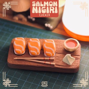 Pode incluir: Uma tábua de sushi de madeira com três nigiris de salmão, pauzinhos, uma pequena tigela de molho e uma porção de wasabi. Os nigiris de salmão têm a parte superior laranja com linhas onduladas brancas. O texto "SALMON NIGIRI CLICKER" está numa caixa vermelha.