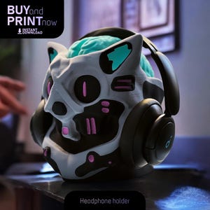 May include: A 3D printed headphone holder shaped like a cat's head with a brain inside. The cat's head is white with black and pink details. The headphones are black with a blue accent.