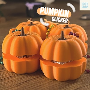 May include: Orange pumpkin-shaped clickers with a textured surface and brown stems. The text "PUMPKIN CLICKER" is displayed on a banner above the pumpkins. Decorative beads are scattered around the pumpkins, suggesting a Halloween theme.