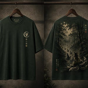 May include: A dark green short-sleeve t-shirt featuring a front graphic of a fox mask within a crescent moon and Japanese text. The back displays a detailed forest scene with a multi-tailed fox, a torii gate, and Japanese text in a dark palette.