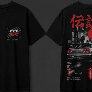 Może przedstawiać: Czarny t-shirt z małym logo GT-R na piersi. Z tyłu znajduje się duża grafika samochodu sportowego, czerwone słońce, japońskie znaki oraz tekst "LEGEND MADE IN JAPAN", "BUILT FOR SPEED DRIVEN BY PASSION" oraz "GT-R".