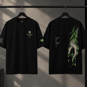 Op de afbeelding: Een zwart t-shirt met korte mouwen en een afbeelding op de voorzijde met een biohazard-symbool en de tekst "POISON N°07". De achterzijde toont een afbeelding van een hand bedekt met druipend groen slijm met de tekst "BEAUTY CAN BE A DEADLY THING".