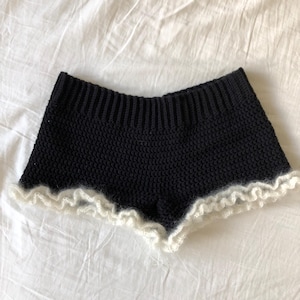 Peut inclure: Short en tricot noir avec une bordure en dentelle crochetée blanche.