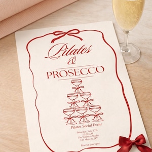 Può includere: Un invito color crema per un evento Pilates & Prosecco, con la scritta "Pilates & Prosecco" in rosso. L'immagine include una pila di calici di champagne, un fiocco rosso, un bicchiere di champagne e un tappetino rosa arrotolato.