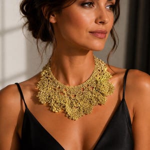 Peut inclure: Un collier en crochet de couleur dorée présentant un motif complexe rappelant la dentelle avec un bord festonné. La pièce est fabriquée à partir de fil métallique fin, créant un design ajouré et texturé qui se porte près du cou en collier large.