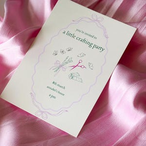 May include: A white invitation card with a purple ribbon and bow. The text reads "You're invited to a little crafting party" with a drawing of scissors, paintbrushes, and butterflies. The date is 8th March, the location is Annabel's house, and the time is 2 pm.