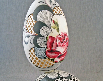 A cut and painted red rose on a huge goose egg sitting on a goose egg stand