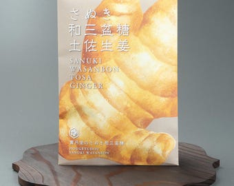 May include: A package of Sanuki Wasanbon Tosa Ginger sweets, with Japanese text and English translations. The packaging features a close-up image of the ginger sweets. The package is displayed on a decorative wooden tray.
