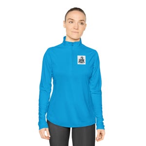 May include: A bright blue long-sleeve athletic shirt with a quarter-zip collar. The shirt features a small square logo on the chest with the words "Dogs Out" in black and white. The shirt is designed for active wear.