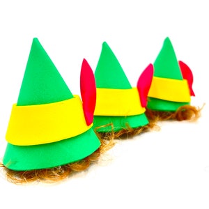 May include: Three green elf hats with yellow trim and red felt pointy ears. The hats have brown fuzzy hair attached to the bottom.