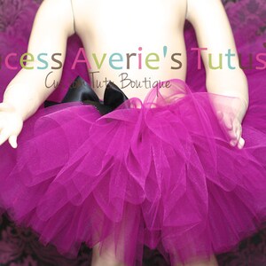 May include: A fuchsia tulle tutu with a black satin bow. The tutu is worn by a child mannequin. The text "Princess Averie's Tutus" is visible in the image.