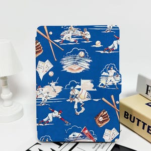 Könnte beinhalten: Eine blaue Baseball-Hülle mit Illustrationen von Baseballspielern, Schlägern, Bällen und einem Stadion. Das Design hat eine Vintage-Ästhetik mit roten, weißen und braunen Akzenten. Die Hülle steht aufrecht.