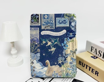 Puede incluir: Una cubierta de cuaderno con estampado azul y blanco con un cisne, pájaros y flores. La cubierta tiene el texto "Enjoy where you are now." impreso en ella.